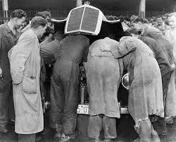 Mechanics leaning over an engine together